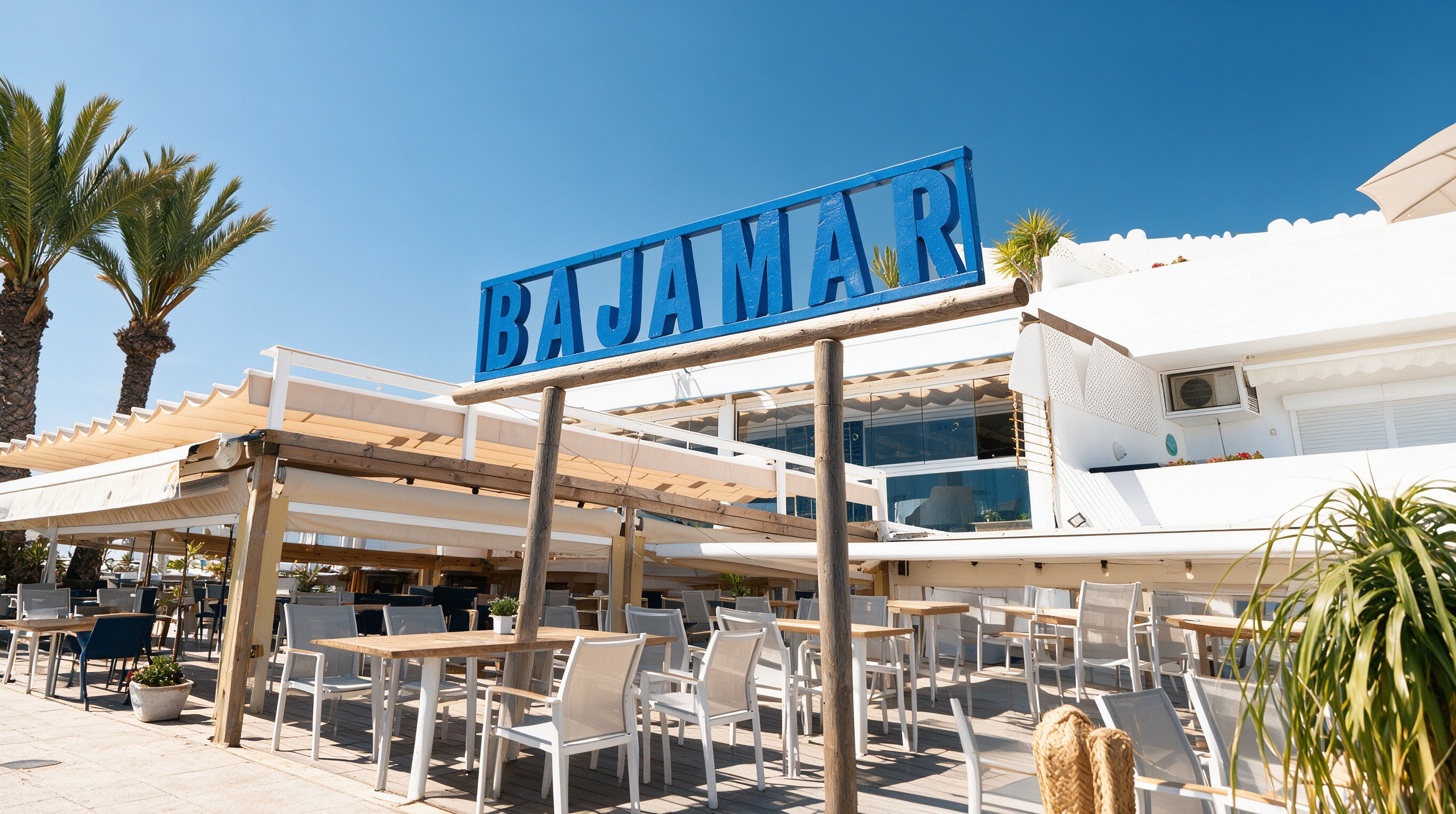 Fachada de Bajamar Bar de playa con su letrero azul, terraza y palmeras